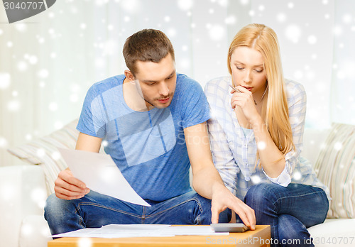 Image of busy couple with papers and calculator at home