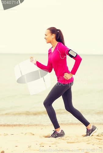 Image of smiling young woman running outdoors