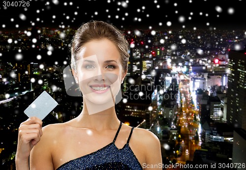 Image of smiling woman in evening dress holding credit card