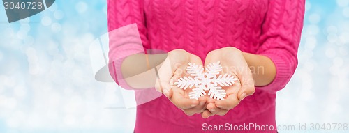 Image of close up of woman in sweater holding snowflake