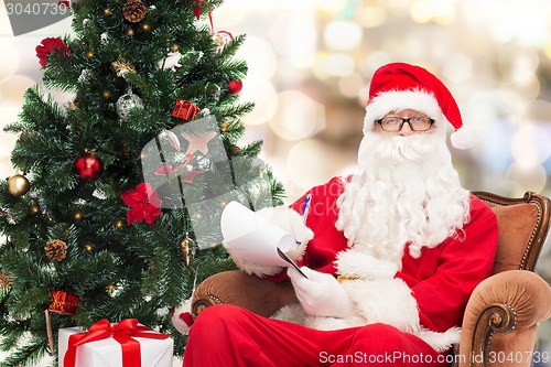 Image of man in costume of santa claus with notepad