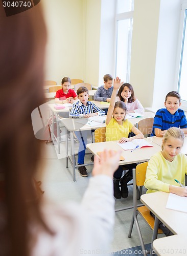 Image of group of school kids raising hands in classroom