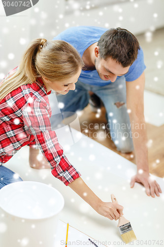 Image of smiling couple smearing wallpaper with glue