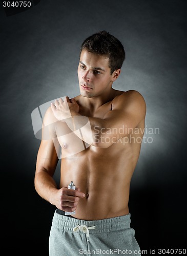 Image of young male bodybuilder applying pain relief gel