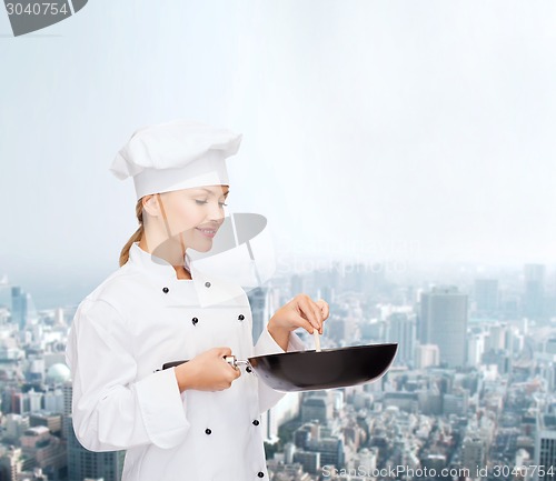 Image of smiling female chef with pan and spoon