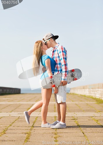 Image of couple with skateboard kissing outdoors
