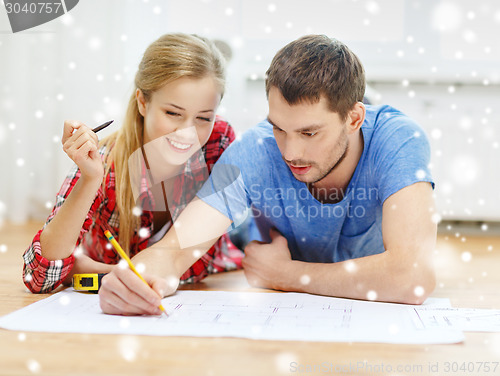 Image of smiling couple with  blueprint at home