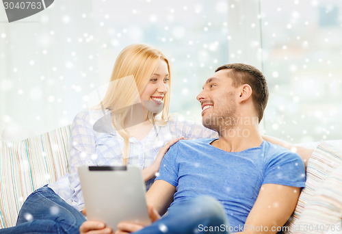 Image of smiling happy couple with tablet pc at home