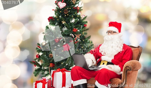 Image of man in costume of santa claus with laptop
