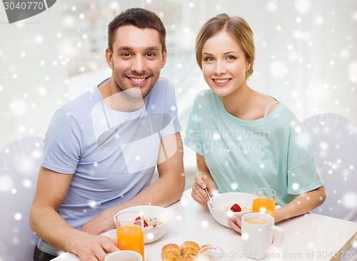 Image of smiling couple having breakfast at home