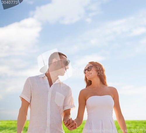 Image of smiling couple in sunglasses walking outdoors