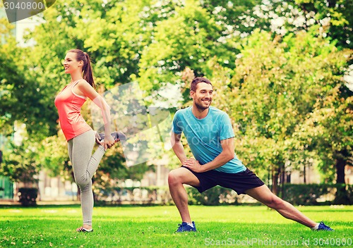 Image of smiling couple stretching outdoors