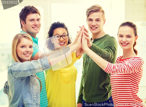 Image of five smiling students giving high five at school