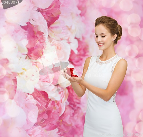 Image of smiling woman holding red gift box with ring