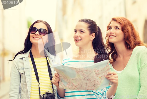 Image of smiling teenage girls with map and camera