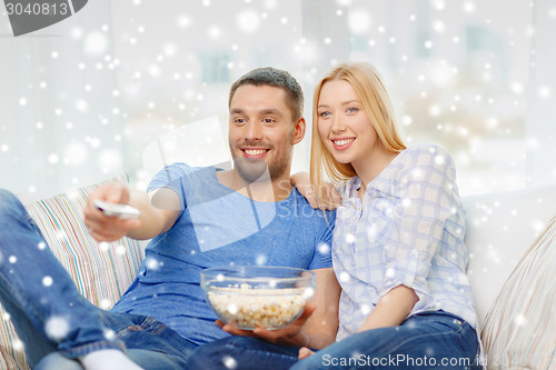 Image of smiling couple watching tv at home