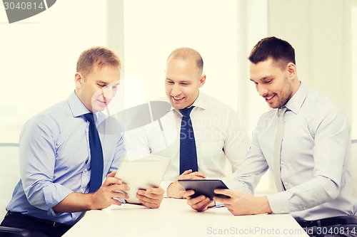 Image of three smiling businessmen with tablet pc in office