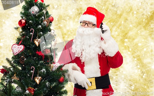 Image of santa claus with smartphone and christmas tree