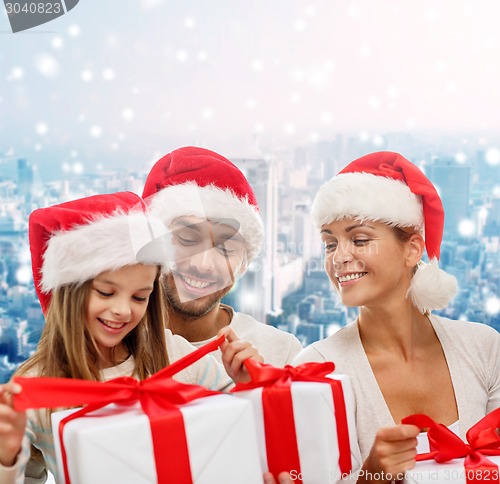 Image of happy family in santa helper hats with gift boxes