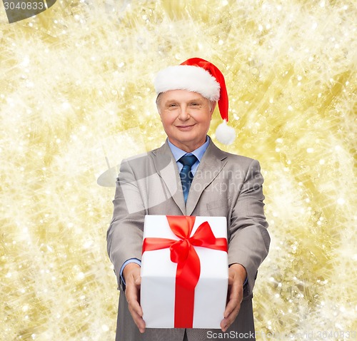 Image of smiling man in suit and santa helper hat with gift