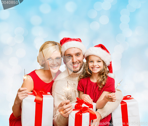 Image of happy family in santa helper hats with gift boxes