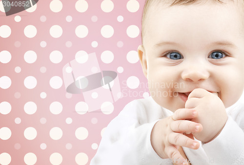 Image of smiling baby girl face over pink polka dots