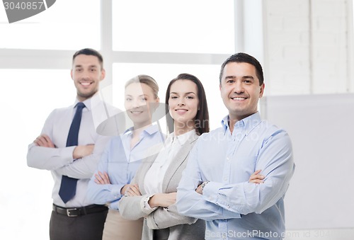 Image of smiling businessman in office with team on back