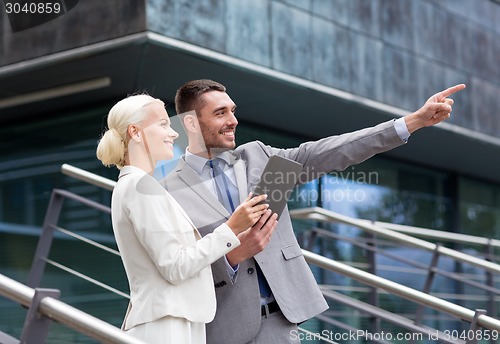 Image of smiling businessmen with tablet pc outdoors