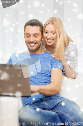 Image of smiling happy couple with laptop at home