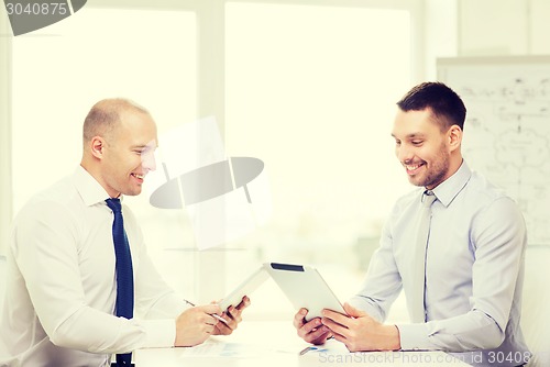 Image of two smiling businessmen with tablet pc in office