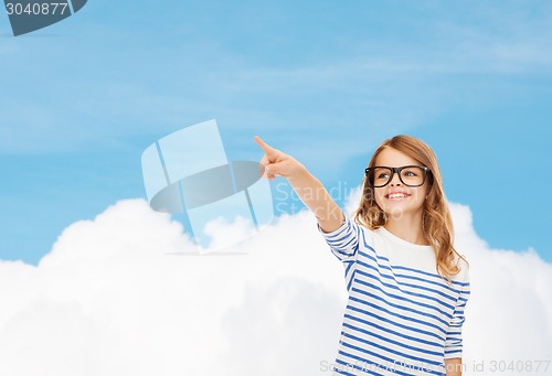 Image of cute little girl in eyeglasses pointing in the air