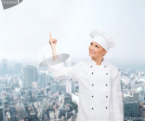 Image of smiling female chef pointing finger to something