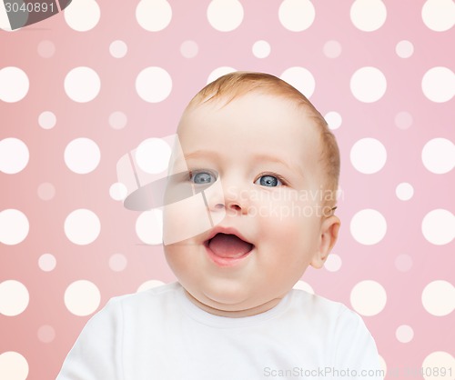 Image of smiling baby girl face over pink polka dots