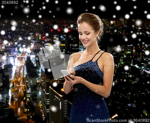 Image of smiling woman in evening dress with smartphone