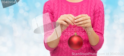 Image of close up of woman in sweater with christmas ball