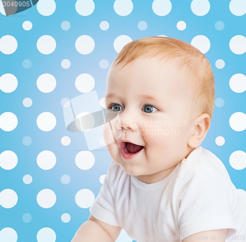 Image of smiling baby boy face over blue polka dots