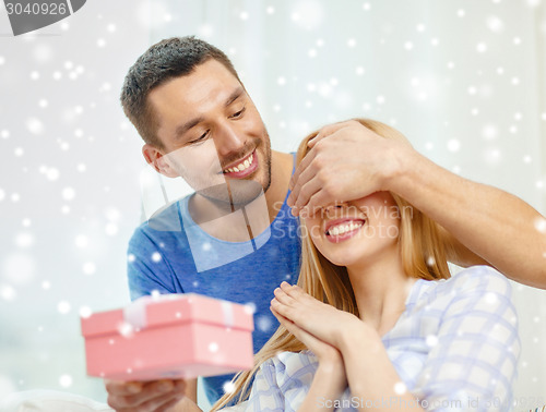 Image of smiling man surprises his girlfriend with present