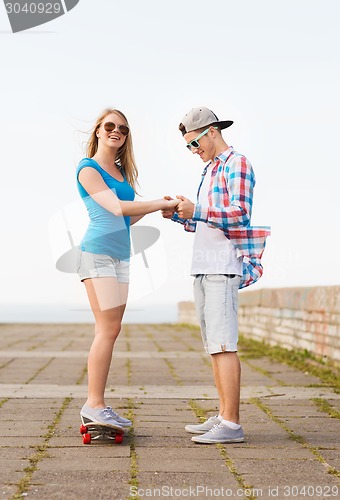 Image of smiling couple with skateboard outdoors