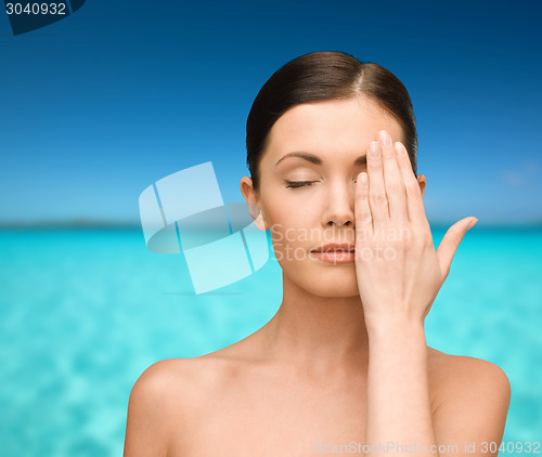 Image of smiling young woman covering face with hand