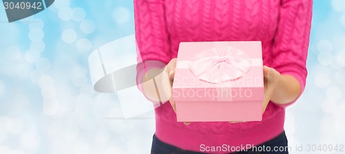 Image of close up of woman in pink sweater holding gift box