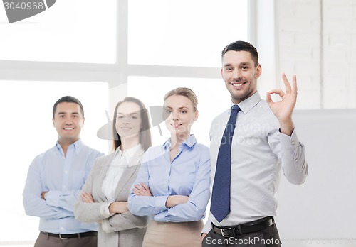 Image of smiling businessman showing ok-sign in office