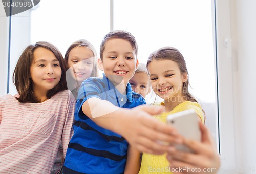 Image of group of school kids taking selfie with smartphone