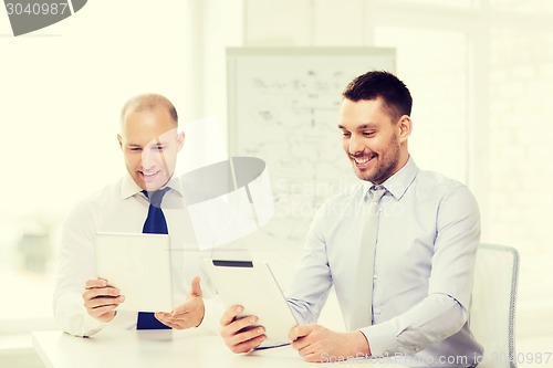 Image of two smiling businessmen with tablet pc in office