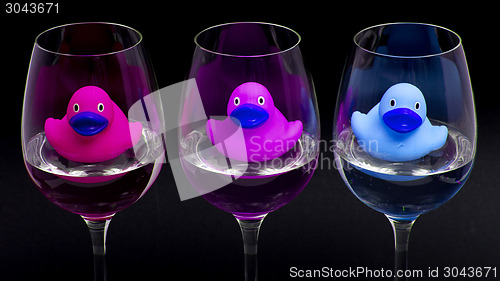 Image of Pink, purple and blue rubber ducks in wineglasses