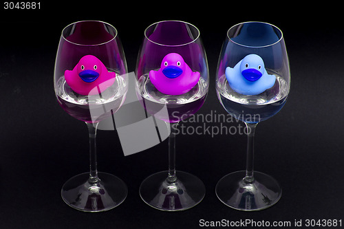 Image of Pink, purple and blue rubber ducks in wineglasses