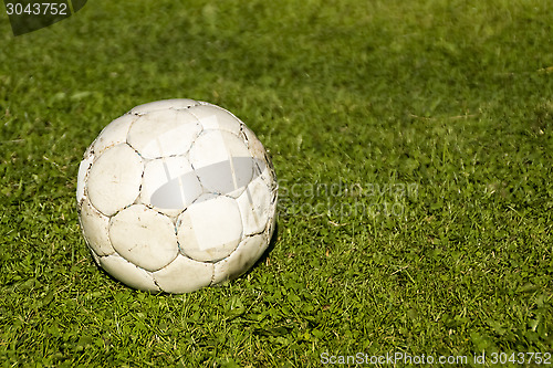 Image of Old shabby ball on green grass