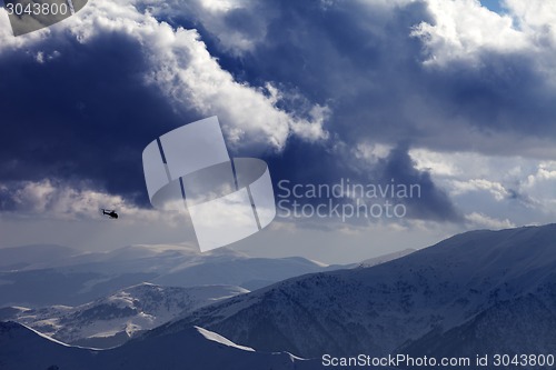 Image of Helicopter in winter mountains and cloudy sky