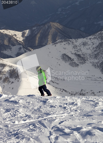 Image of Snowboarder on off-piste slope in sun evening