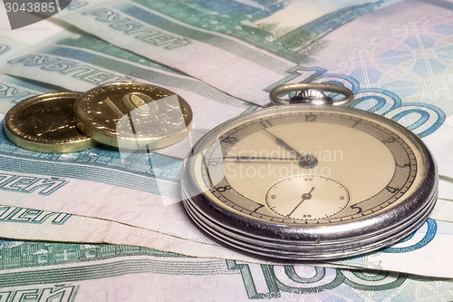 Image of Vintage watch and coins on banknotes