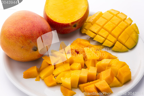 Image of Heap Of Juicy Mango Cubes And Whole Fruit On Plate